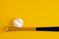 Wooden baseball bat and a ball on yellow background Royalty Free Stock Photo