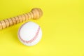 Wooden baseball bat and ball on yellow background, space for text. Sports equipment Royalty Free Stock Photo