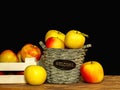 Wooden basket and crate with fresh colorful apples on dark background Royalty Free Stock Photo