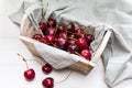 Wooden basket of fresh cherries in a grey cotton serviette at white background Royalty Free Stock Photo