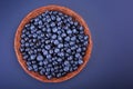 A wooden basket with juicy and bitter blueberries on a dark purple background, top view. A crate full of berries.