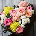 Wooden basket in the shape of a heart with pink roses and white, yellow flowers stands on a stand against Royalty Free Stock Photo