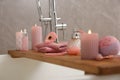 Wooden bath tray with candles and personal care products on tub, closeup Royalty Free Stock Photo