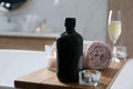 Wooden bath tray with shower gel, candles and fresh towel on tub indoors Royalty Free Stock Photo