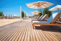 a wooden beach deck with sun loungers and parasols