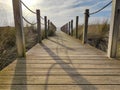 Wooden beach path with rope fence and blue sky, leading to ocean. Low angle. Royalty Free Stock Photo