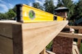 A wooden beam made of fresh timber with yellow carpentry tools - a water level for accurate marking on a summer day against the Royalty Free Stock Photo