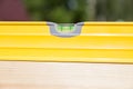 A wooden beam made of fresh timber with yellow carpentry tools - a water level for accurate marking on a summer day against the Royalty Free Stock Photo