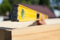 A wooden beam made of fresh timber with yellow carpentry tools - a water level for accurate marking on a summer day against the Royalty Free Stock Photo