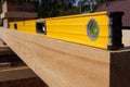 A wooden beam made of fresh timber with yellow carpentry tools - a water level for accurate marking on a summer day against the Royalty Free Stock Photo