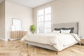 Wooden bedroom with frame canvas, bed and linens, beige walls and window Royalty Free Stock Photo