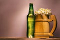 wooden beer mug with fine daisies similar to foam and a green full bottle with a metal lid Royalty Free Stock Photo