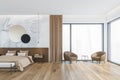 Wooden beige bedroom with bed on parquet floor and armchairs near window Royalty Free Stock Photo