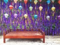 Wooden bench in background with hanging Chinese lanterns of different colors. Chinese style fabric pendant lamps on purple Royalty Free Stock Photo