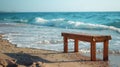 Wooden bench on the beach with sea and waves in the background Royalty Free Stock Photo