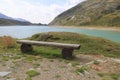 Wooden bench, bench at the reservoir Monte Spluga, at the SplÃÂ¼gen Pass, and surrounding mountains in summer Royalty Free Stock Photo