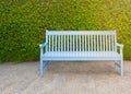 Wooden bench blue color on green leaves background
