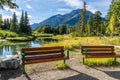 Wooden bench on Bow River riverside. Bow River Trail in summer time. Mount Norquay in the background. Banff National Park. Royalty Free Stock Photo