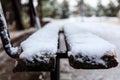 Wooden bench covered with snow in a park waits for companionship. Close up, blur background, banner Royalty Free Stock Photo