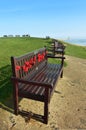 A wooden bench decorated with Remembrance Day poppies with a seascape in the background Royalty Free Stock Photo