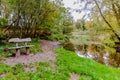 Wooden bench at the edge of a quiet river with reflection in the water Royalty Free Stock Photo