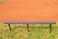 Wooden bench, empty seats on outdoor tennis court.