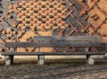 A wooden bench in front of a very artful brick wall Royalty Free Stock Photo