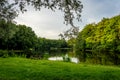 Wooden bench on green grass overlooking a water pond at Haagse B