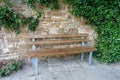 Wooden bench beside an ivy-clad sandstone wall Royalty Free Stock Photo