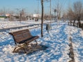 Wooden bench located on a snowy walk