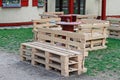 Wooden bench made of pallets for sitting with tables made from coil of electric cable