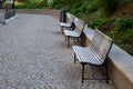 Wooden bench near the edge of the path in the park pedestrian blocks pavement retaining wall low metal frame benches elegant shape Royalty Free Stock Photo