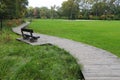 Wooden bench near pathway in beautiful public city park Royalty Free Stock Photo