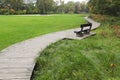 Wooden bench near pathway in beautiful public city park Royalty Free Stock Photo