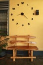 Wooden bench near yellow wall. Vintage wooden bench under the wall clock Royalty Free Stock Photo