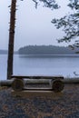 Wooden bench next to a blue misty lake in Finland