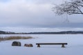 Wooden bench next to the frozen lake. Winter landscape from Finland Royalty Free Stock Photo