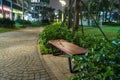 Wooden bench in the park at night with green tree surrounding Royalty Free Stock Photo