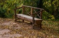Wooden bench on a path full of leaves at the bottom of trees in autumn Royalty Free Stock Photo