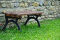 Wooden bench placed on the lawn with a river stone background. Royalty Free Stock Photo