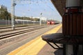 wooden bench on the railway platform for comfortable waiting on the background of rails and two trains in the distance. ground