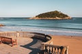Wooden bench on seashore in San Sebastian, Spain. Beach called La Concha with tourists, balcony and bench. Royalty Free Stock Photo