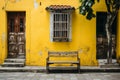 a wooden bench sitting in front of a yellow building Royalty Free Stock Photo