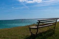 Wooden bench on a sunny day with a kite surfer on the sea in the background and a clear blue sky Royalty Free Stock Photo