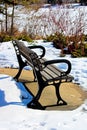 A wooden bench in winter with no snow underneath it