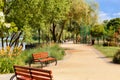 Wooden benches on the Dnipo embankment along the cobbled walking path of the city green park on a summer day