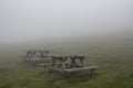 Wooden benches and grass field in fog.