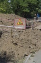 Wooden billboard with sign carrying out repair earthworks next to the dug trench Royalty Free Stock Photo