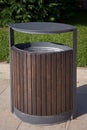 Wooden bin beside street in the public park. Trash or garbage can setting on a cobble stone pavement in a park . Wooden decorate o