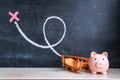 Wooden biplane toy and pink piggy bank in the form of a pig on the background of the blackboard